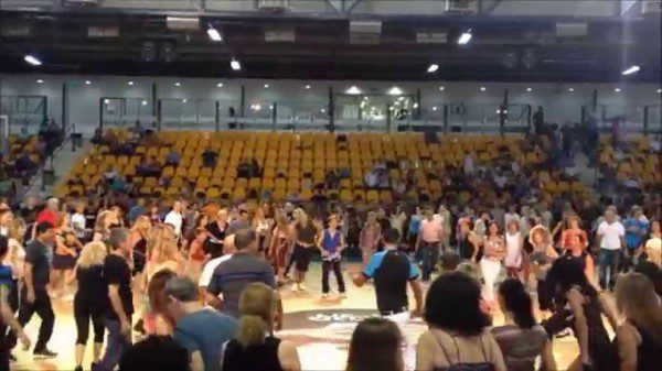 A crowd of people in an arena with one person standing on the floor.